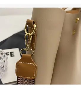 Dettaglio dei ganci in metallo dorato e pelle testurizzata sulla borsa tote beige