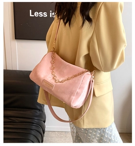 Detail of pink Boston bag with golden chain strap and leather handle shown on model