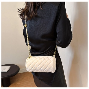 Detail of white quilted cylinder bag with gold chain and adjustable metal ball