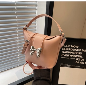 Détail du sac à main en cuir rose orné d'un élégant nœud décoratif en métal argenté