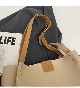 Dettaglio della borsa tote beige con inserti in pelle marrone e borchie dorate