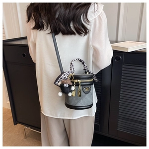 Détail du sac seau matelassé avec poignée foulard à damier et charm monstre en peluche