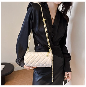 Detail of white quilted cylinder bag with gold chain strap and adjustable ball buckle