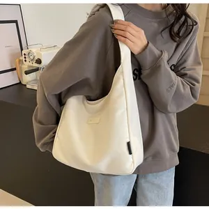 Detail of BANATU cream corduroy hobo bag featuring leather logo patch and crescent shape