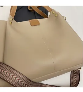 Dettaglio della borsa tote beige in pelle con manici marroni e finiture dorate lucide