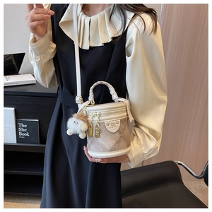 Détail du sac seau blanc en cuir avec poignée tressée et breloque en peluche
