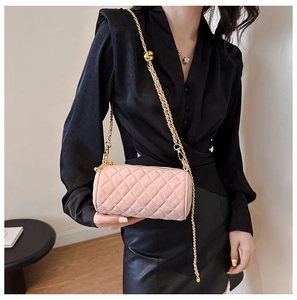 Pink quilted cylinder bag with gold chain strap worn as a stylish crossbody detail