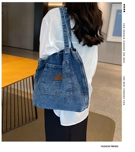 Close-up of washed denim tote bag with side pocket and brown leather patch detail