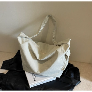 Détail d'un sac fourre-tout en nylon crème avec large bandoulière et poche latérale pratique