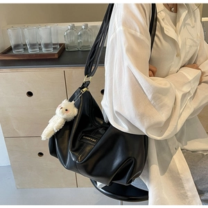 Detail of black pleated tote bag with fashion label and white plush bunny charm