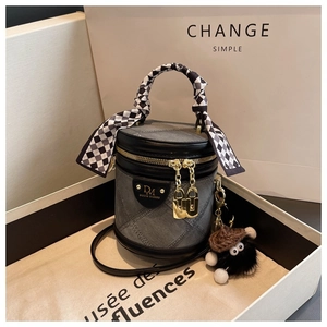 Détail d'un sac seau en denim matelassé avec poignée en foulard et pendentif en peluche