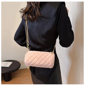 Detail of pink velvet cylinder bag with gold chain strap on a black silk outfit