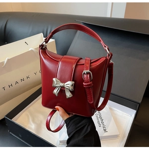 Détail du sac seau en cuir bordeaux avec nœud en métal argenté et bandoulière