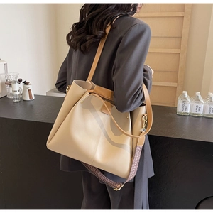 Beige tote bag detail showing the wide patterned shoulder strap and premium gold hardware