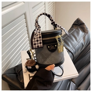 Détail du sac seau cylindrique avec poignée en foulard et breloque monstre en peluche