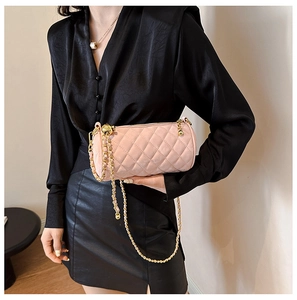 Detail of pink quilted cylinder bag with golden metal chain strap and spherical hardware