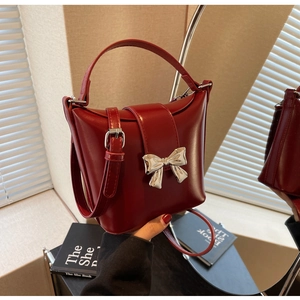 Détail du sac seau en cuir rouge avec nœud en métal argenté et poignée assortie