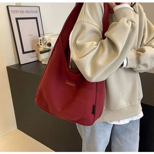 Detail shot of burgundy canvas hobo bag with BANATU leather label and wide shoulder strap