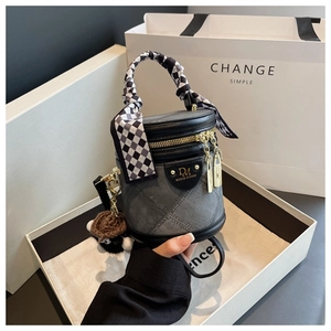 Détail du sac seau en denim gris avec poignée en foulard et breloque ours en peluche
