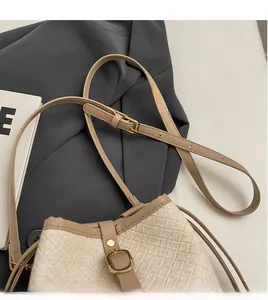 Detail of adjustable leather strap and golden buckle on woven straw bucket bag
