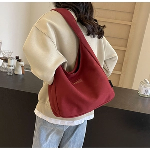 Detail of burgundy canvas hobo bag with BANATU leather logo and wide shoulder strap