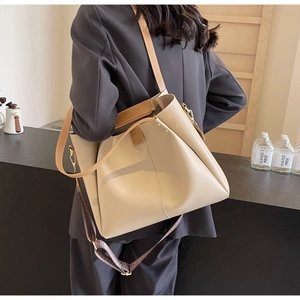 Detail of large beige tote bag with wide geometric woven strap and leather texture