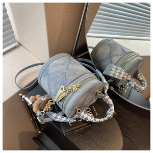 Détail d'un sac seau en denim bleu clair avec foulard à carreaux et pendentif doux