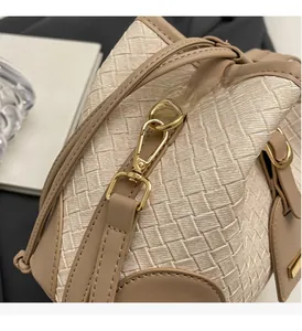 Detail of woven bucket bag featuring cream PU texture and gold metal hardware