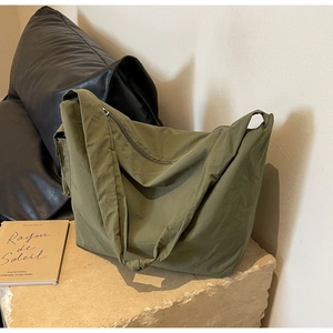 Détail du sac fourre-tout en toile vert armée avec bandoulière large sur surface en pierre