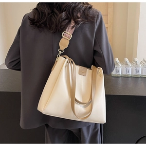 Detail of off-white tote bag with wide geometric strap and brown leather handles