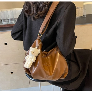 Detail of dark brown pleated hobo bag with adjustable strap and cute bear charm