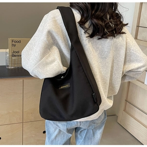 Detailed back view of a black canvas tote bag with BANATU brand label on wide shoulder strap