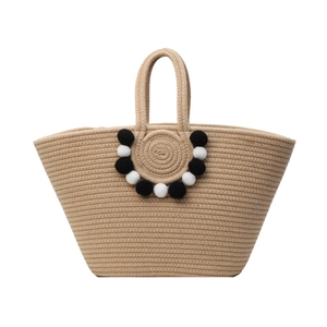 Natural woven straw tote bag with black and white pom poms for beach vacation use