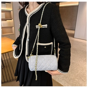 Close-up of quilted cylinder bag with gold chain strap on tweed jacket