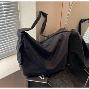 Détail du sac cabas en toile noire montrant la poche latérale et la bandoulière nouée