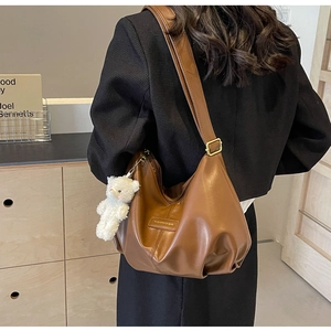 Detailed shot of brown pleated tote bag featuring matte leather texture and cute bear charm