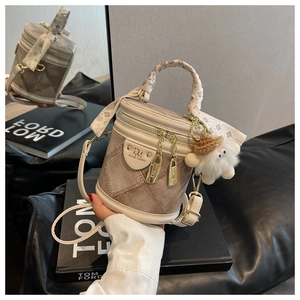 Détail d'un sac seau matelassé beige avec breloque ours en peluche et foulard en soie