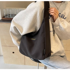 Detail shot of the black canvas hobo bag with BANATU logo on a gray hoodie model