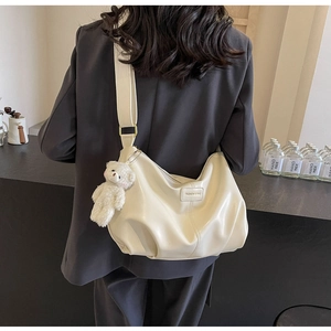 Detail of soft cream leather tote with pleated texture and cute plush bear charm