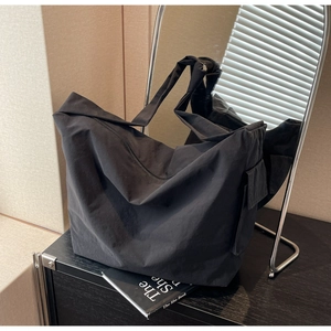 Gros plan d'un grand sac cabas noir en nylon avec poche latérale sur une table en bois