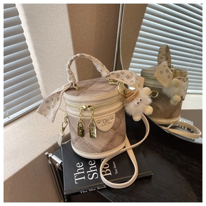 Détail du sac cylindrique à texture losange avec foulard en soie et pendentif peluche