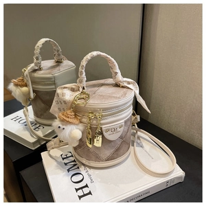 Détail du sac seau à carreaux avec poignée en foulard et pendentif en peluche sur livres