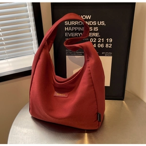 Close-up of burgundy canvas hobo tote bag with brand leather patch on a metal table