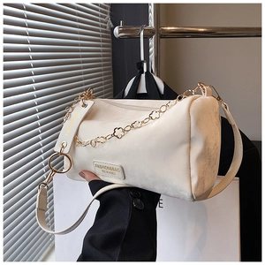 Detail of white suede cylinder bag featuring decorative gold floral metal chain