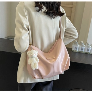 Detailed view of pink pleated hobo bag with teddy bear pendant on a female model