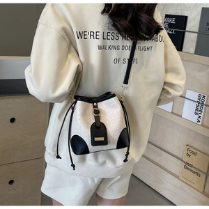 Detail view of woven bucket bag with black leather trim and drawstring on model