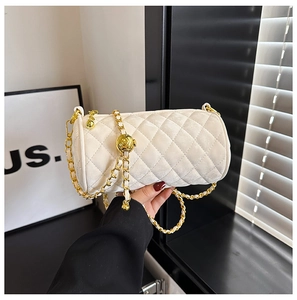 Close-up of beige quilted cylinder bag with gold chain strap and metal ball adjuster