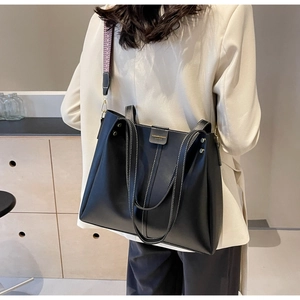 Close-up of black leather tote bag with stylish wide patterned strap for shoulder wear