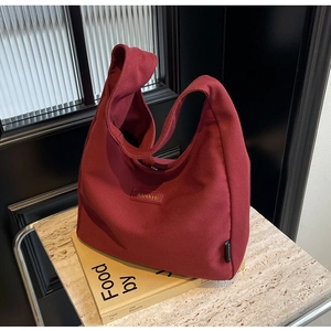 Detail of burgundy canvas tote bag on marble surface with wide shoulder strap