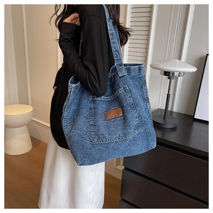 Close-up of the denim tote bag featuring a leather patch detail and washed texture